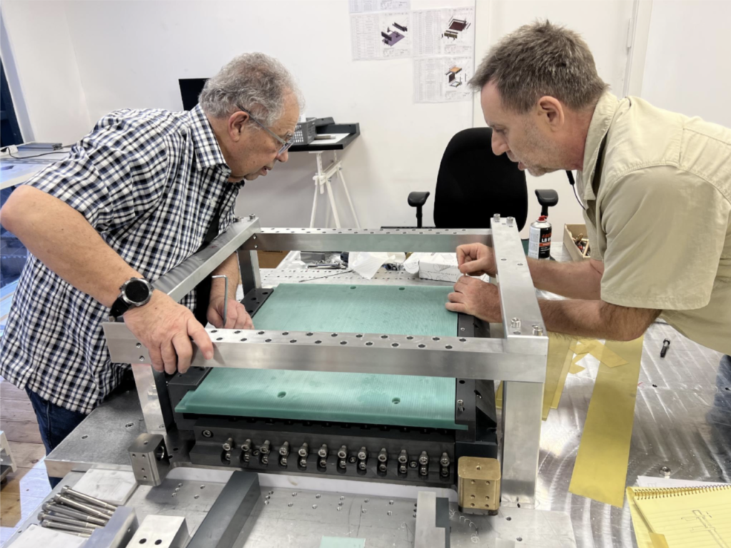 Two engineers assembling the magnet frame in the workshop
